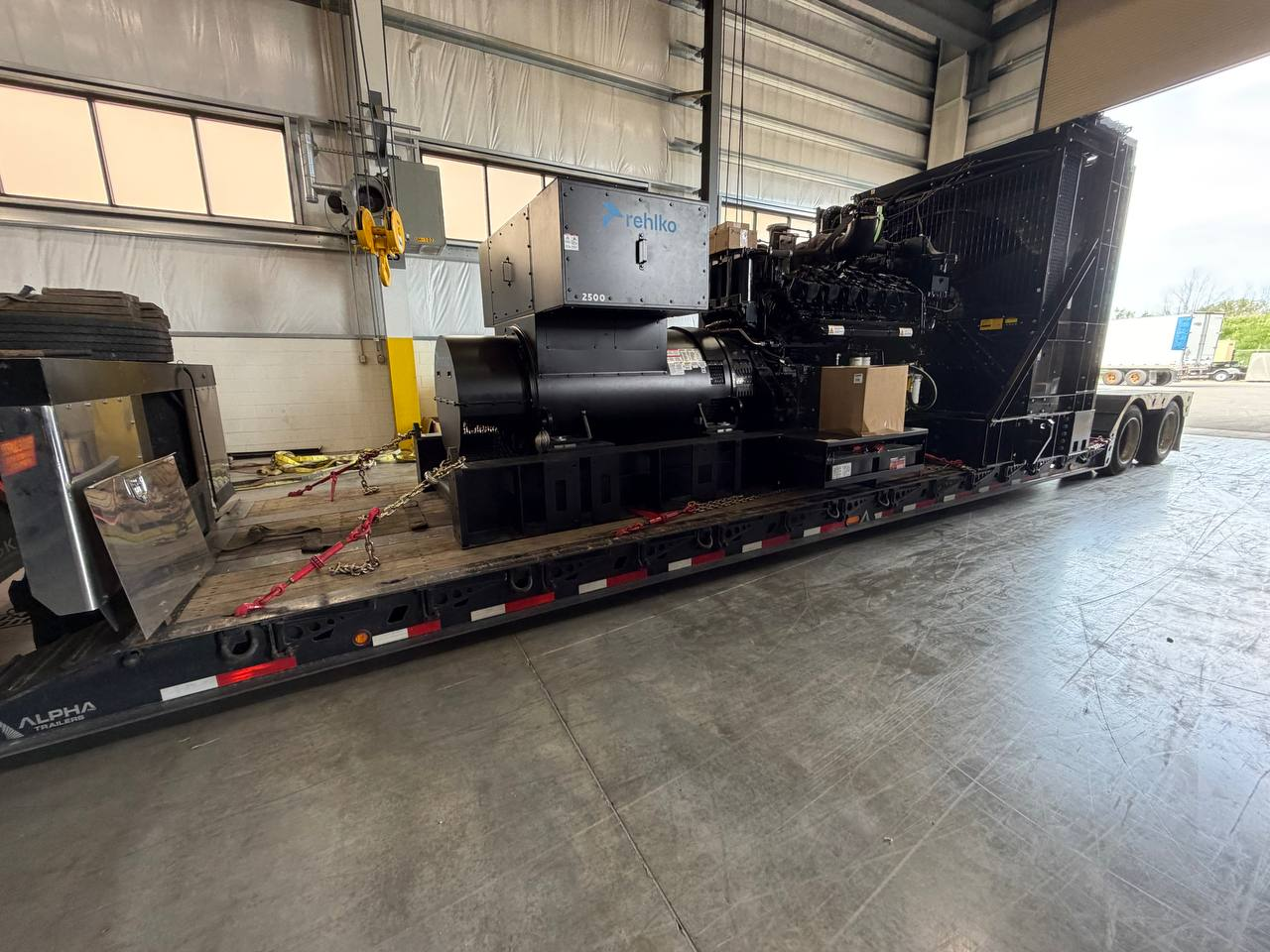 Large generator unit chained and strapped on an open flatbed trailer