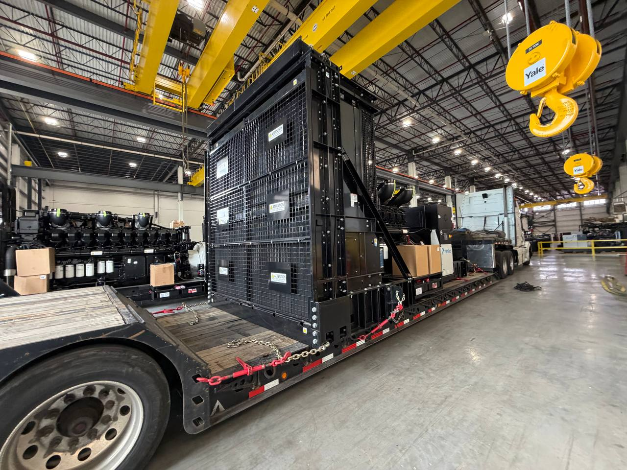 Industrial machinery secured on a flatbed trailer inside a warehouse terminal